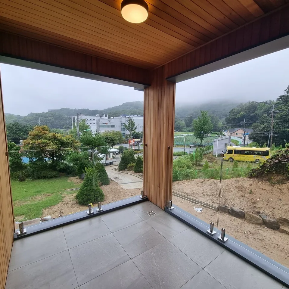 경기 용인 주택 실내 — 목재 천장과 바깥 풍경이 보이는 코너 창